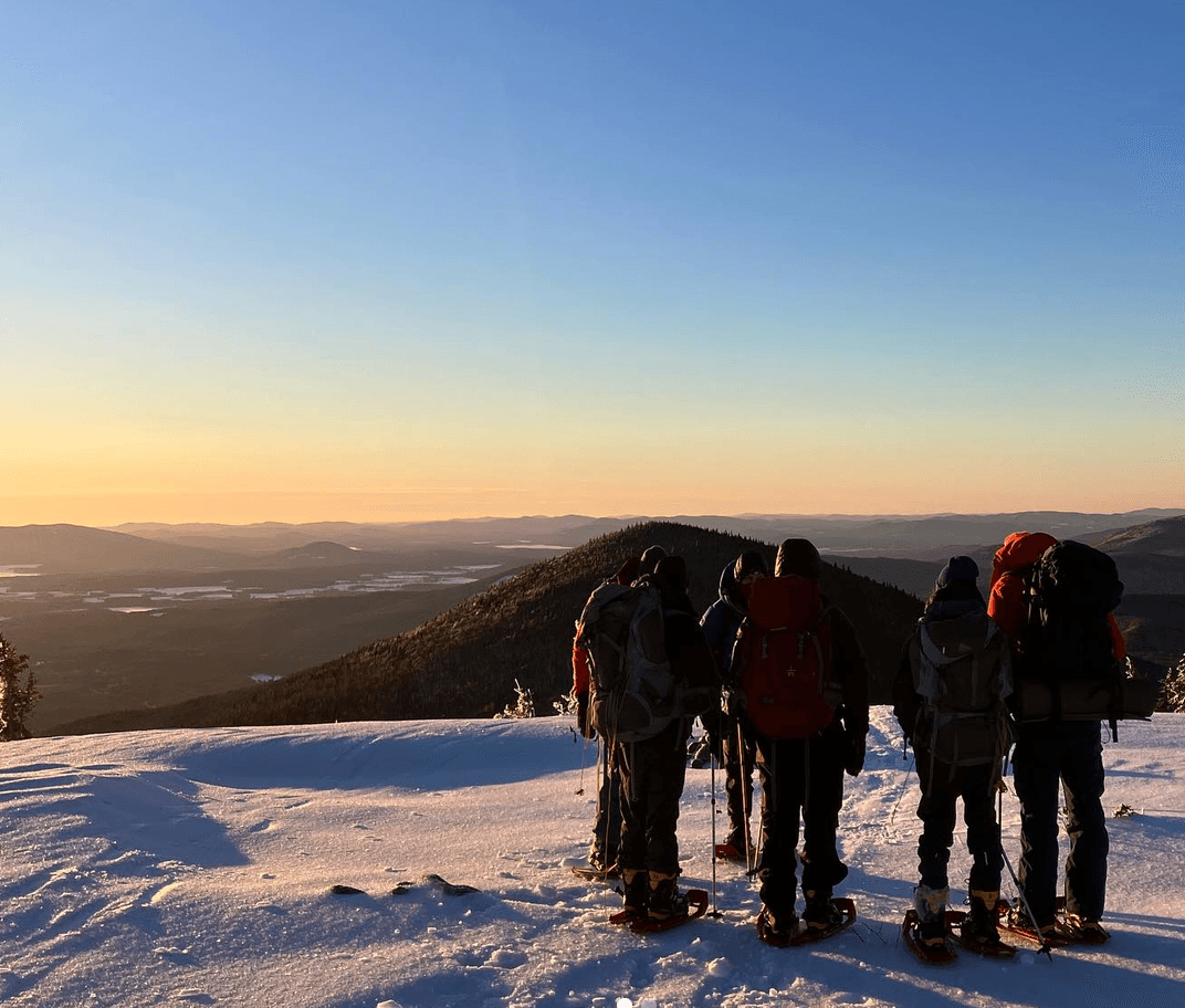 A group of young people hike on a snowy mountain with the Rippleffect team