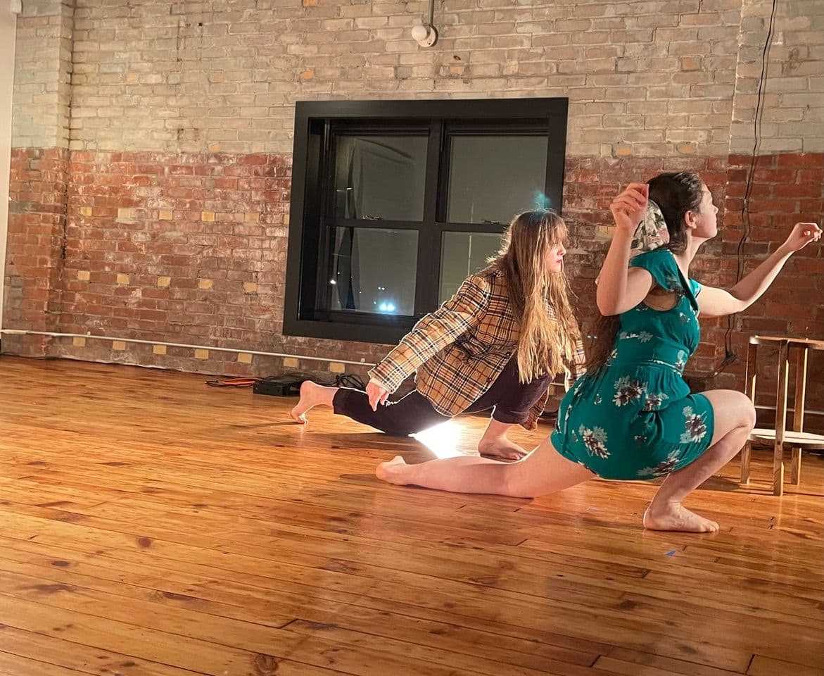 Two dancers perform work on a wooden floor